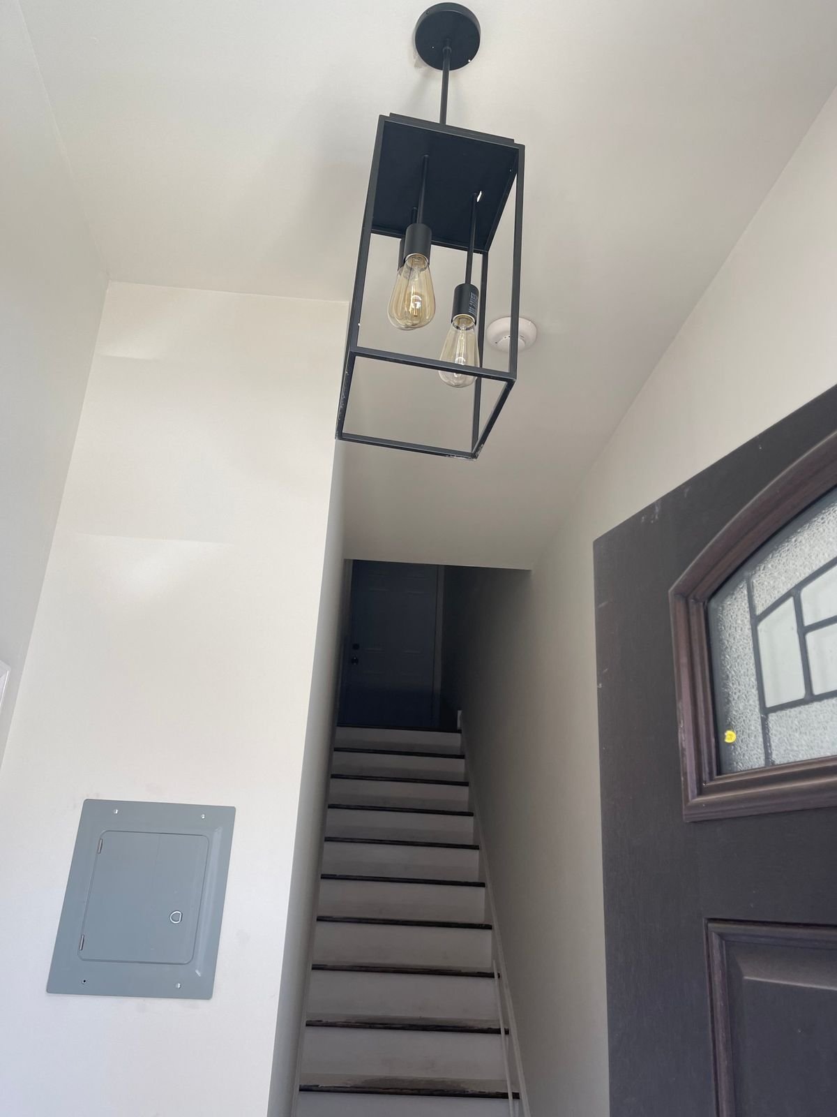 A black lantern pendant with LED lamps hanging above a stairway.