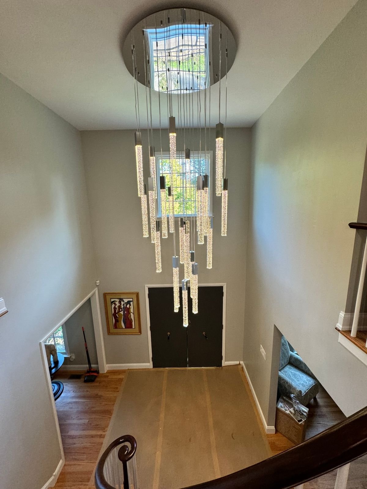 A tall LED chandelier hanging through a two-story foyer above the front door.