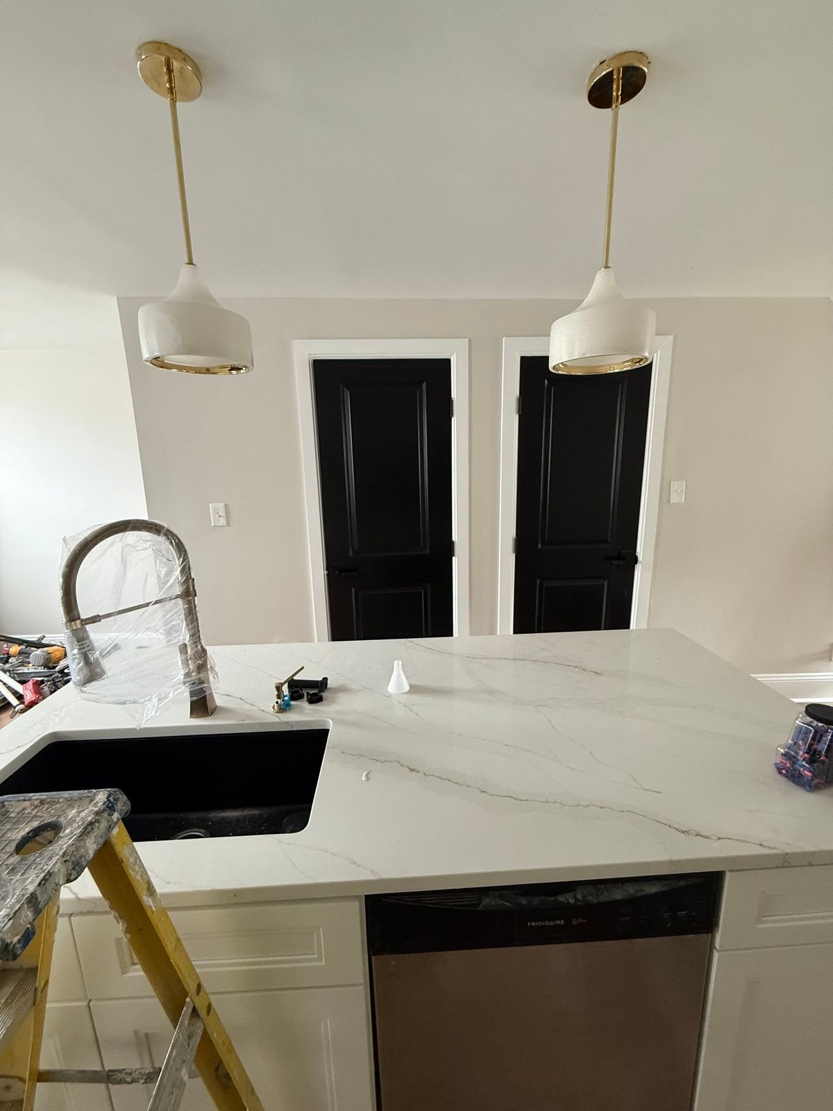 Two white pendant lights hung over a new kitchen island with a quartz countertop.