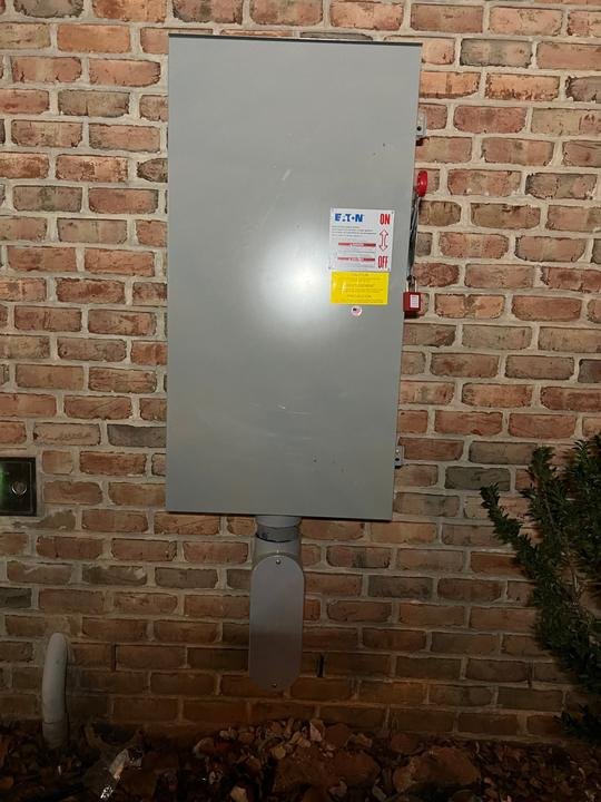 An Eaton safety switch mounted on brick with a lockout on the handle, so the power can be shut off at the wall.